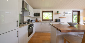 Bright, modern kitchen with grey cabinets, wooden island, and stainless appliances under a panelled ceiling.